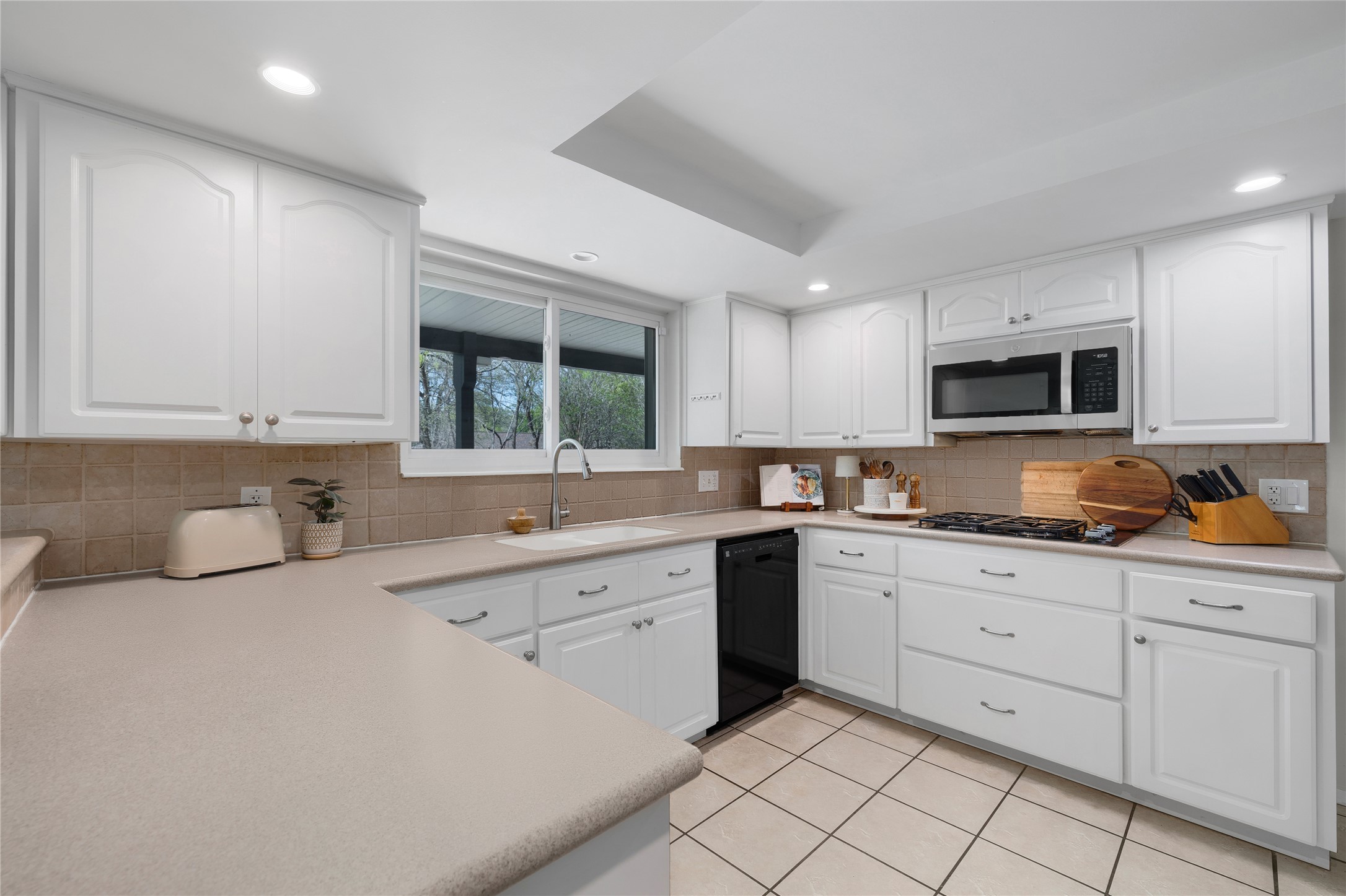 2403 Comburg Castle Way Austin, TX 78748 - Photo 19 of 40 Kitchen with white cabinetry, light countertops, stainless steel microwave, light tile patterned floors, and recessed lighting