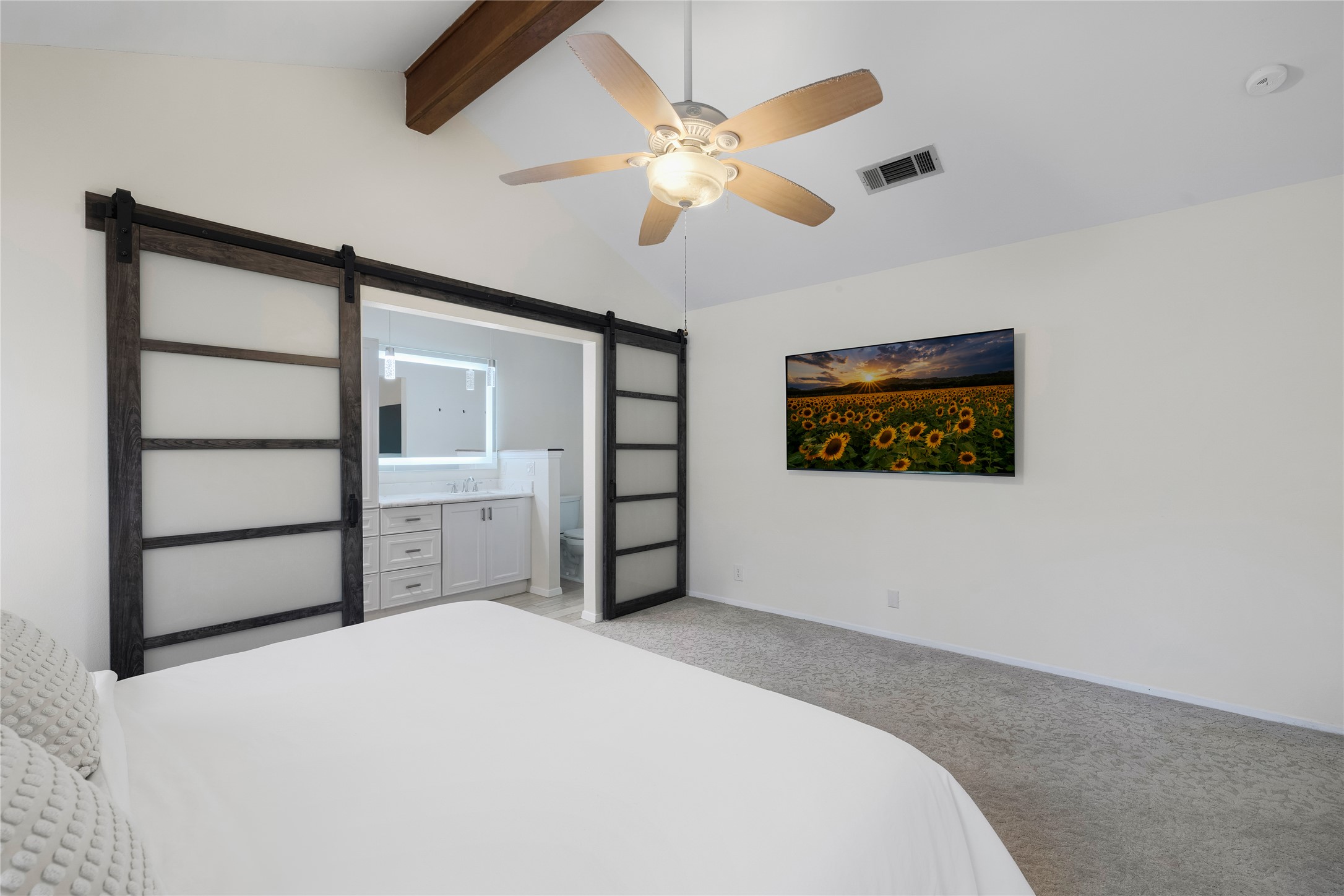 2403 Comburg Castle Way Austin, TX 78748 - Photo 23 of 40 Bedroom with a barn door, light carpet, ensuite bath, beamed ceiling, and a ceiling fan