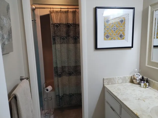 a bathroom with a granite countertop sink and a shower