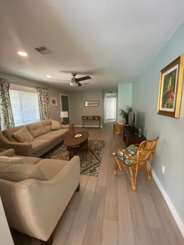 a living room with furniture kitchen view and a wooden floor