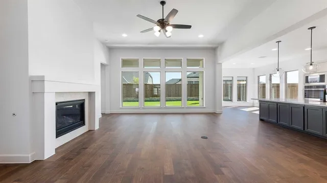 a view of a kitchen and an empty room with wooden floor