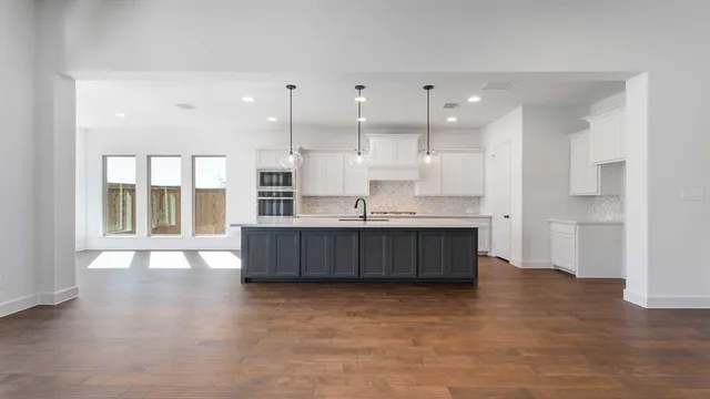 a large kitchen with stainless steel appliances granite countertop a large counter top a stove and a wooden floors