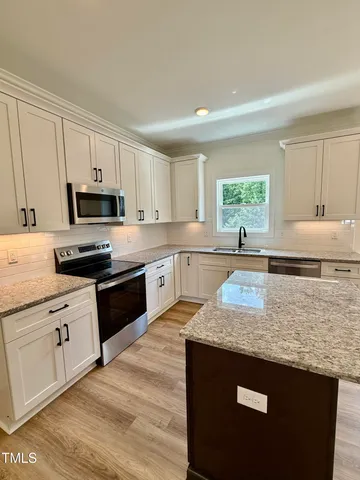 a kitchen with granite countertop a stove a sink dishwasher and a granite counter top