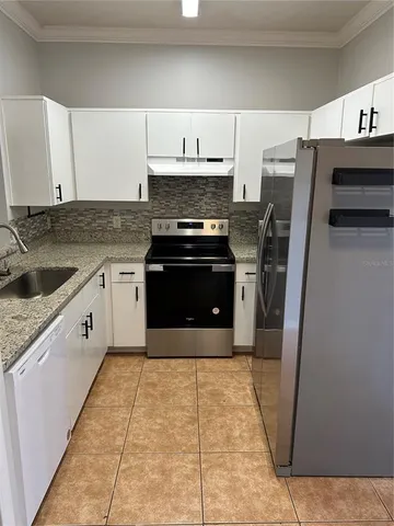 a kitchen with granite countertop a sink stove and refrigerator