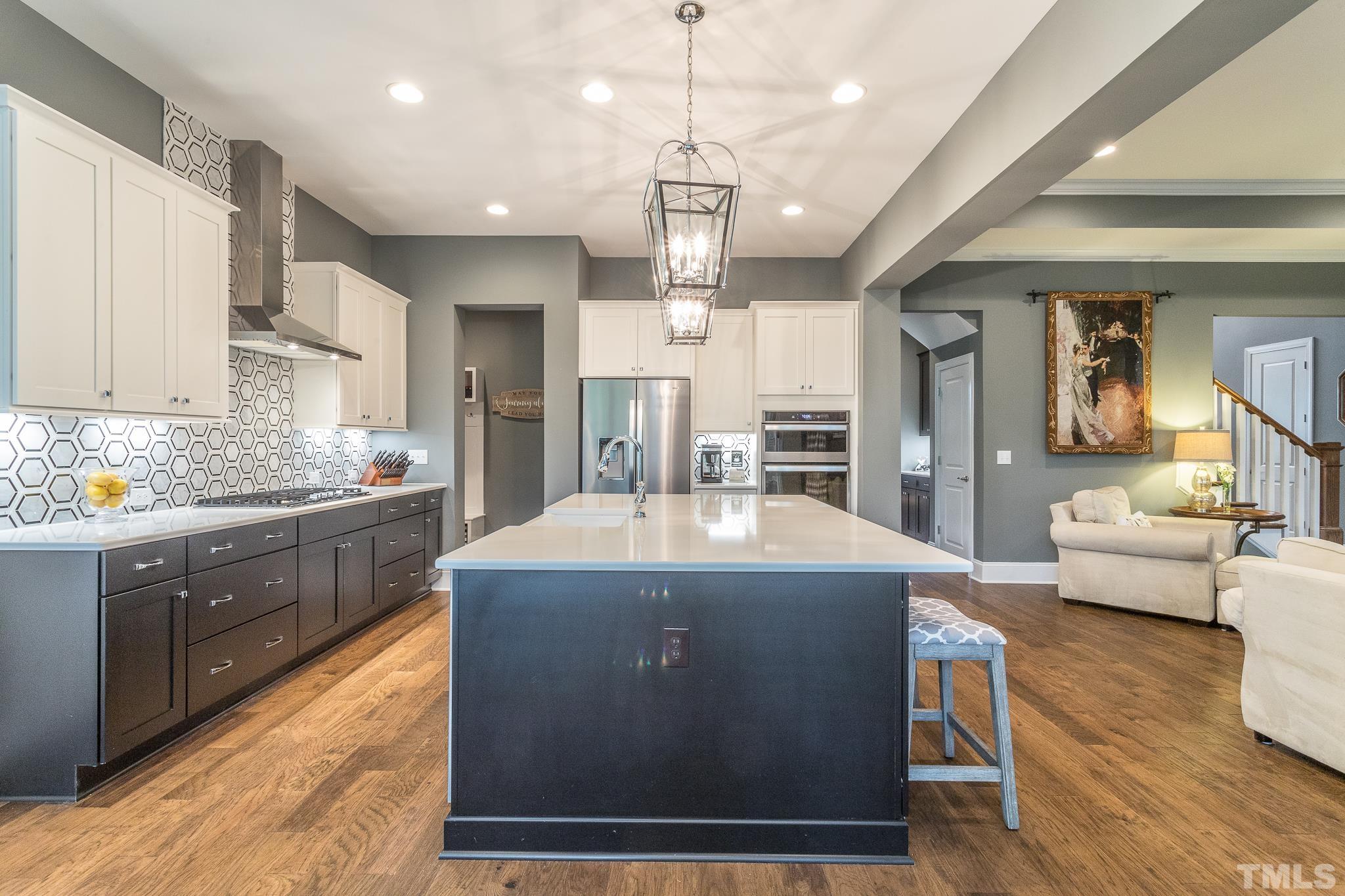 5281 Aleppo Lane Raleigh, NC 27613 - Photo 22 of 57 a kitchen with kitchen island granite countertop a stove a sink a refrigerator and white cabinets with wooden floor