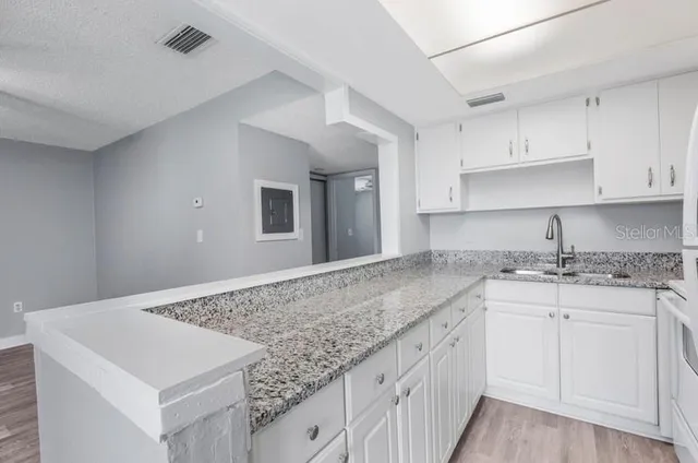 a kitchen with granite countertop white cabinets and sink