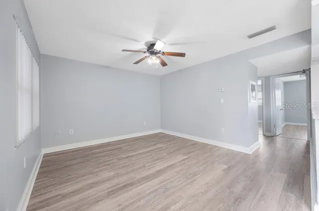 a view of a room with wooden floor and a ceiling fan