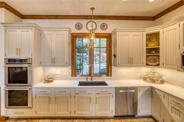 a kitchen with stainless steel appliances granite countertop a stove top oven a dining table and chairs with wooden floor