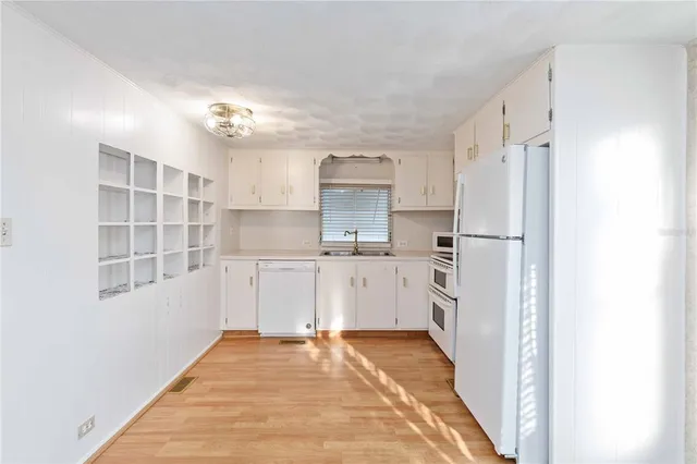 a kitchen with white cabinets and refrigerator