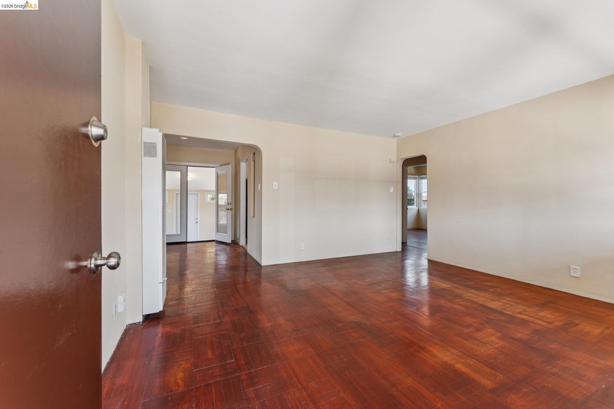 2879 Rheem Avenue Richmond, CA 94804 - Photo 7 of 45 Spacious room featuring wood-finish flooring, light-toned wall paint, and multiple arched doorways