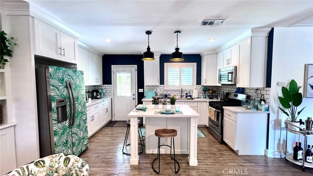 a kitchen with a refrigerator a stove cabinets dining table and chairs