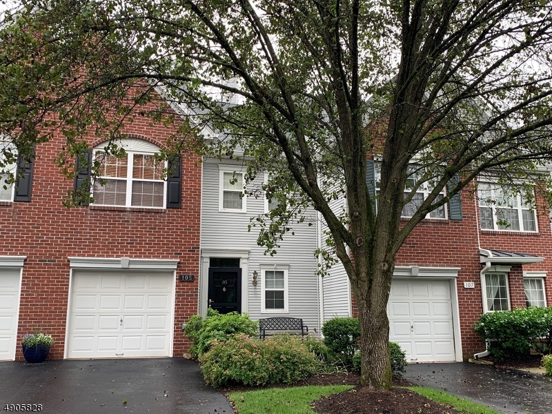 a front view of a house with a tree