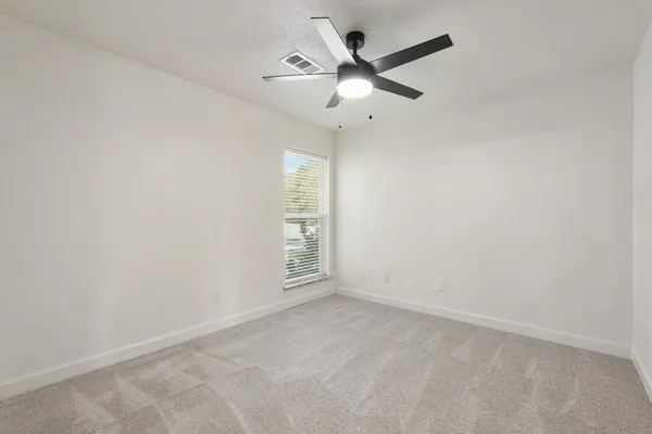 en empty room with ceiling fan and window