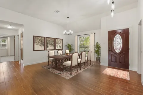an empty room with windows chandelier and fireplace