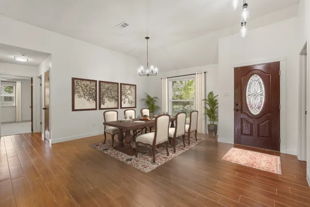 an empty room with windows chandelier and fireplace