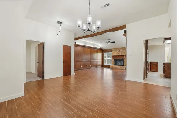 an empty room with windows chandelier and fireplace