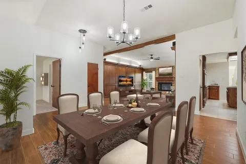 a view of an empty room with wooden floor and a ceiling fan