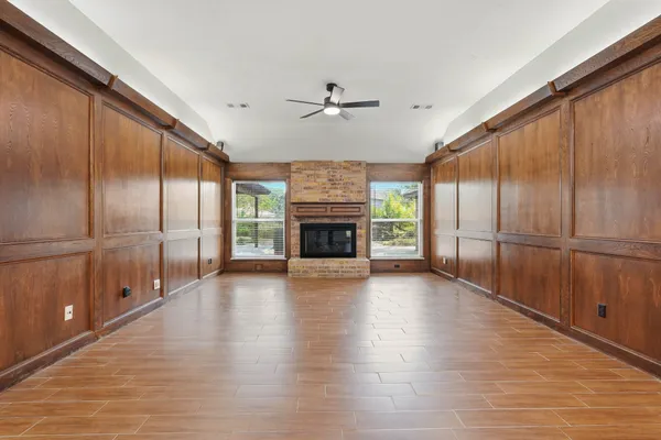 a view of an empty room with wooden floor and a ceiling fan