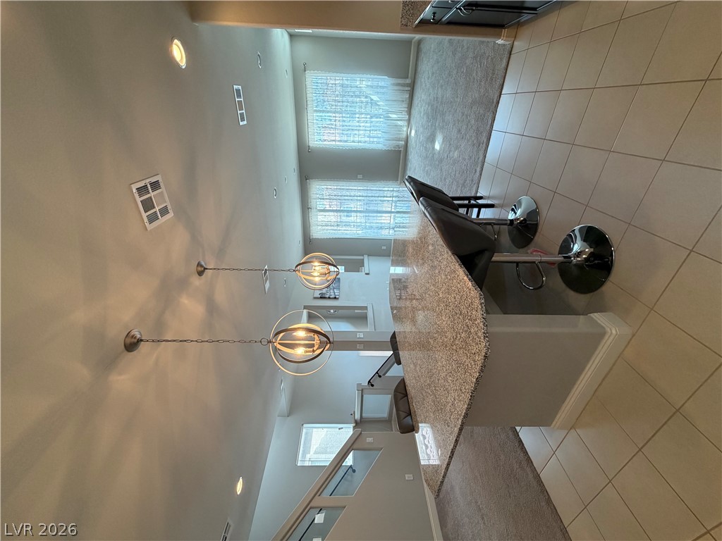 6385 Jackson Spring Road Las Vegas, NV 89118 - Photo 2 of 36 An inviting kitchen island provides ample counter space, perfectly complemented by a well-lit living area.