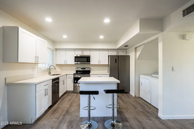 a kitchen with a sink a counter top space stainless steel appliances and cabinets