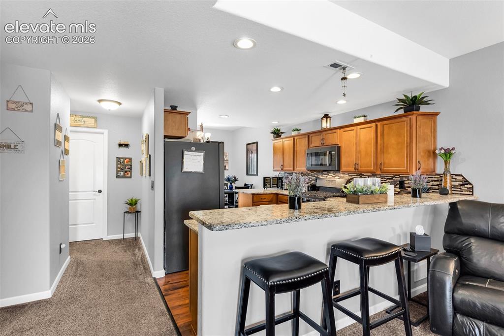 415 Empire Road Canon City, CO 81212 - Photo 12 of 40 a kitchen with stainless steel appliances granite countertop dining table chairs sink and wooden floor