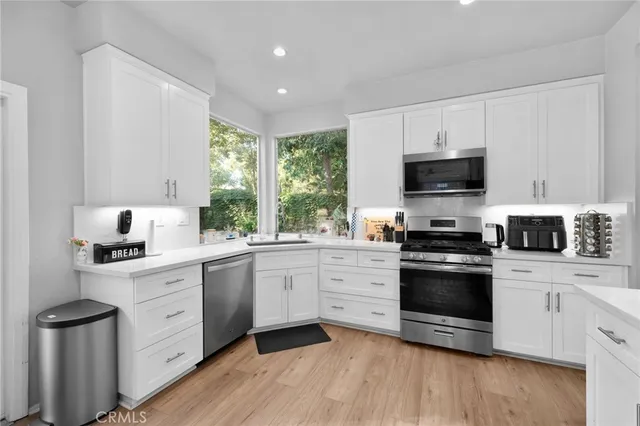 a kitchen with cabinets stainless steel appliances a sink and a window
