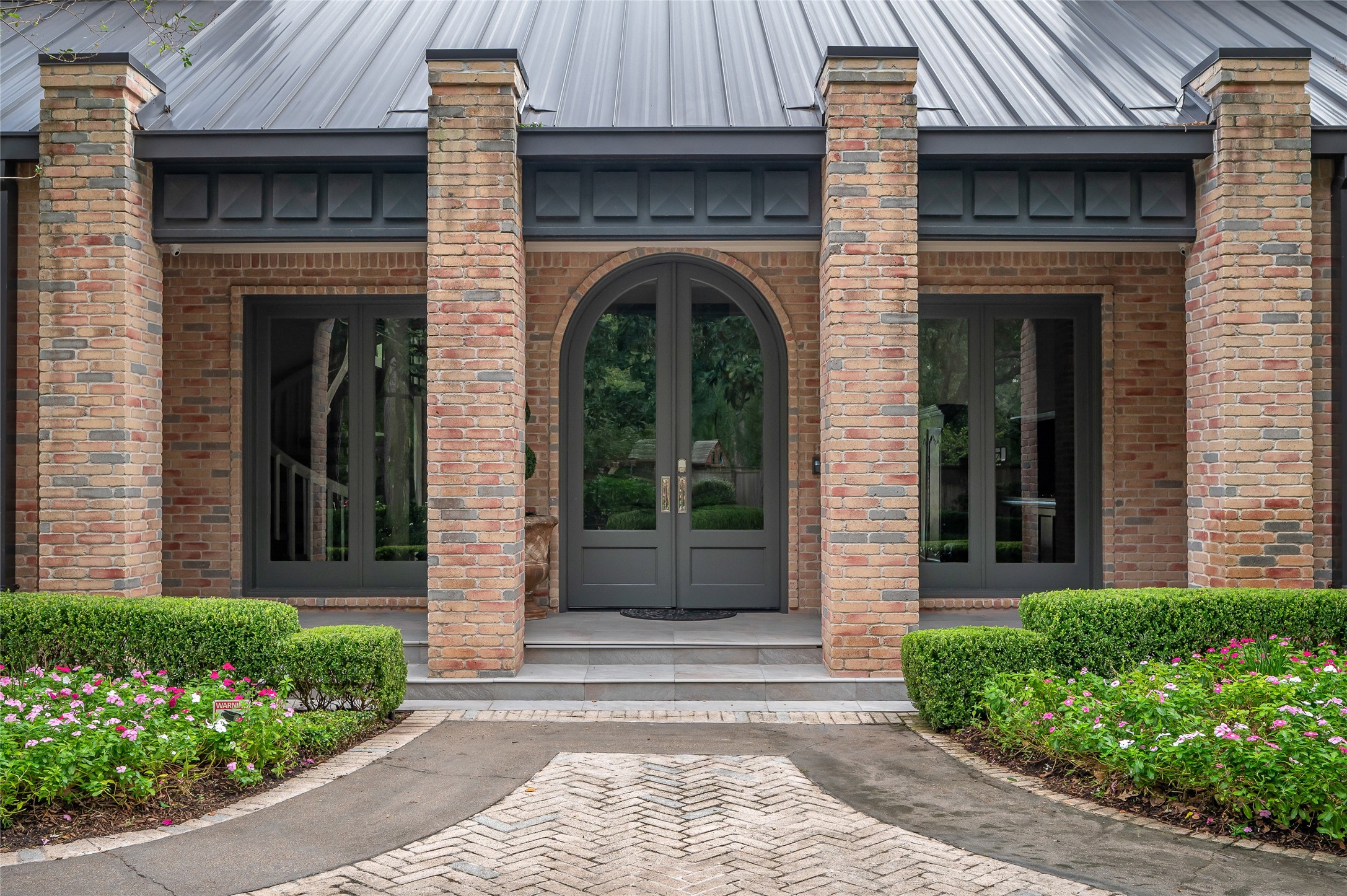 11518 Shadow Way Street Houston, TX 77024 - Photo 3 of 50 The home’s front elevation exudes timelessness and splendor, featuring four grand brick pillars, a scenic drive, lush landscaping, and an inviting seating area that together create a striking first impression.
