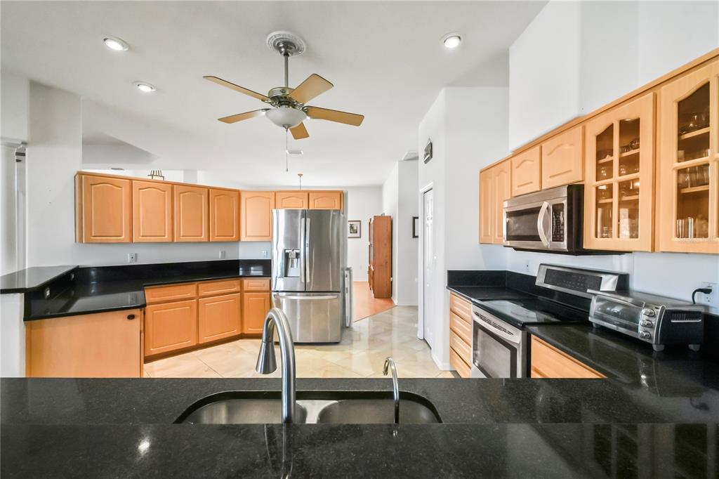 3441 Cedar Crest Loop Spring Hill, FL 34609 - Photo 19 of 58 a kitchen with stainless steel appliances granite countertop a refrigerator a stove and a sink with wooden floor