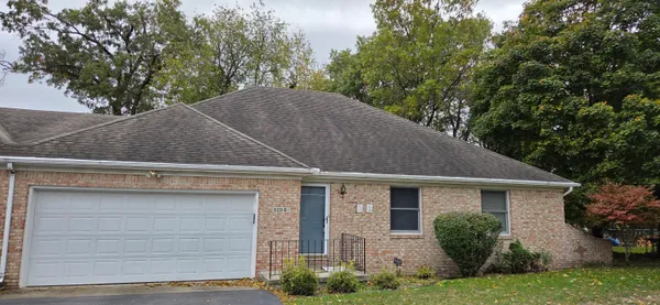 a view of a house with a yard plants and large tree