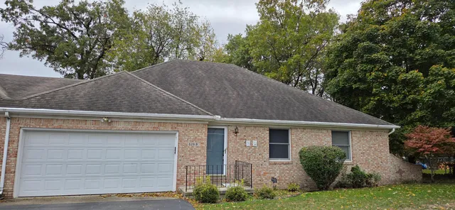 a view of a house with a yard plants and large tree
