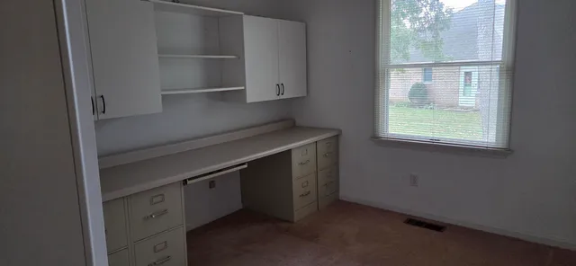 a view of a room that has a large window and wooden floor