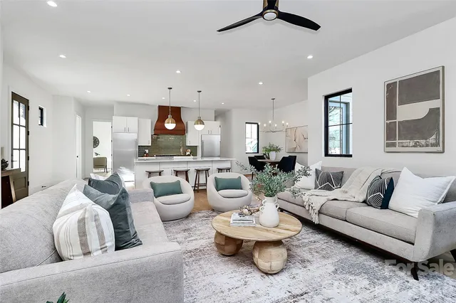 a large white kitchen with a large island oven a stove a dining table and chairs