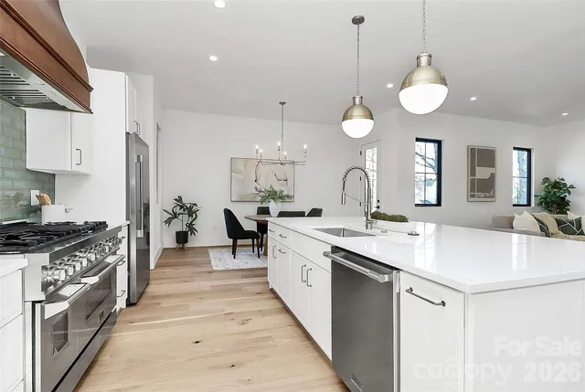 a kitchen with stainless steel appliances kitchen island granite countertop a table chairs and a wooden floor