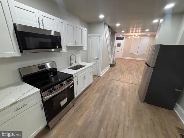 a kitchen with stainless steel appliances a refrigerator a sink a stove a microwave a counter top and cabinets