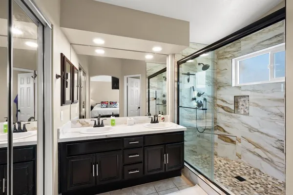 a bathroom with a double vanity sink mirror and shower