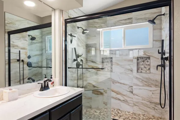 a bathroom with a sink mirror and shower