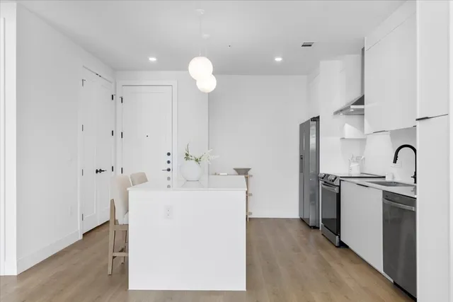 a large white kitchen with a sink and refrigerator