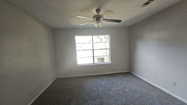 an empty room with a window and a fan