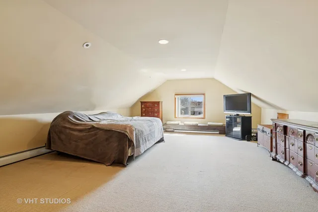 a spacious bedroom with a bed and a flat tv screen on dresser