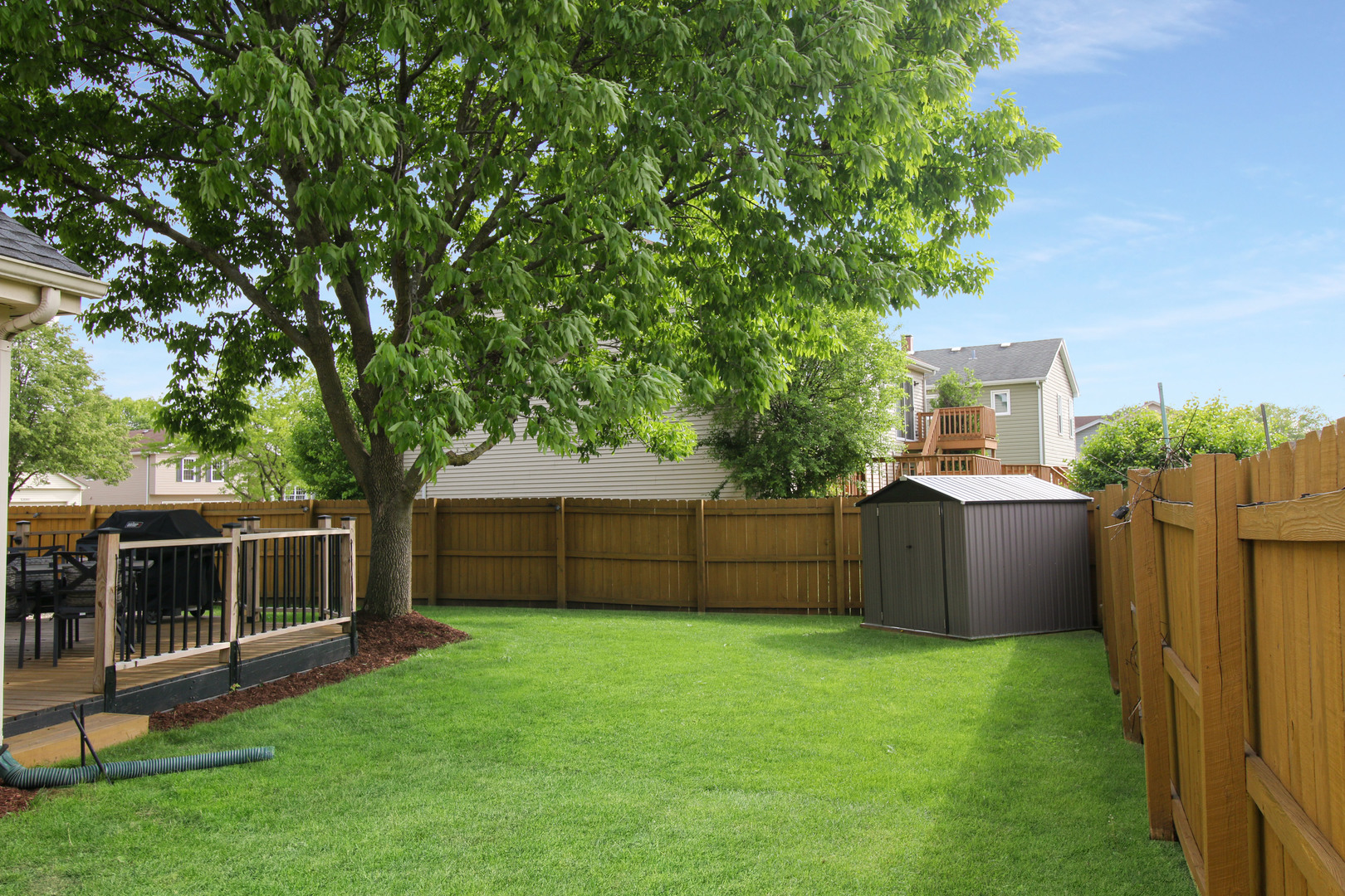 574 Foxford Road Bartlett, IL 60103 - Photo 5 of 22 a view of a backyard with a large tree and wooden fence