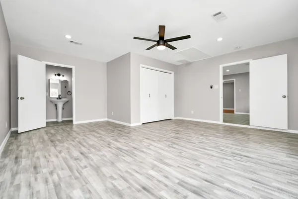 a view of empty room with wooden floor and ceiling fan