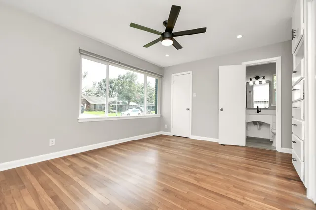 a view of empty room with wooden floor and fan