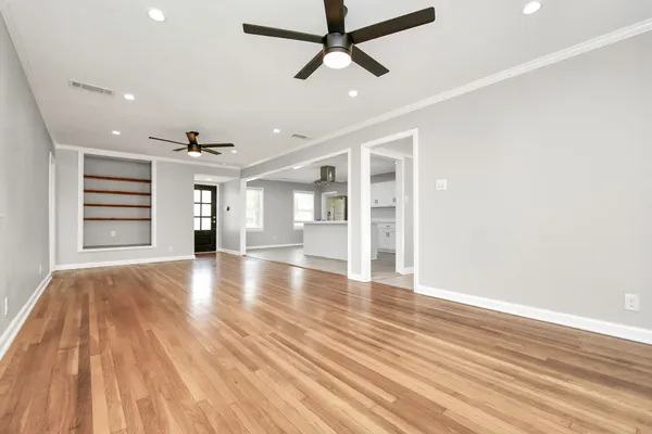 a view of empty room with wooden floor and fan