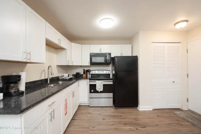 a kitchen with granite countertop a refrigerator and a stove top oven