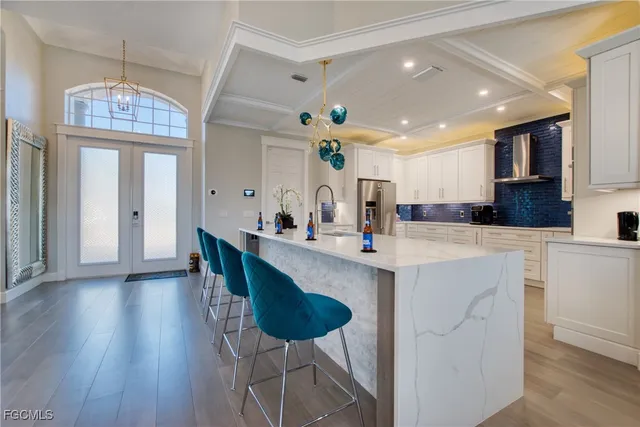 a kitchen with stainless steel appliances kitchen island granite countertop a table chairs and a chandelier