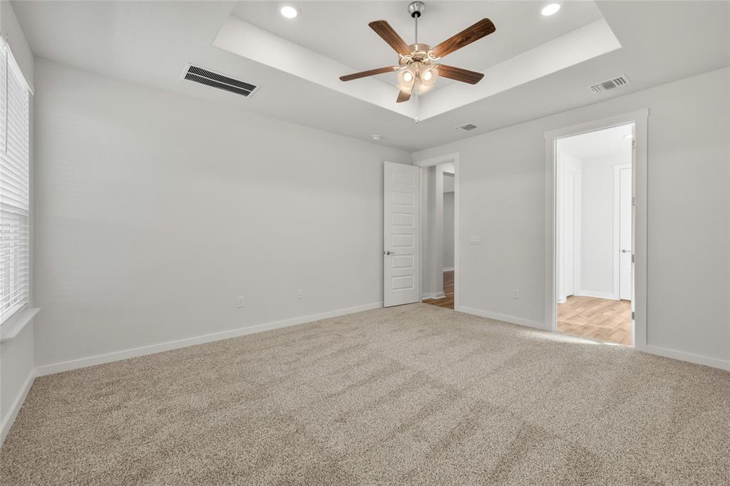113 Shadow Oak Cove Georgetown, TX 78628 - Photo 20 of 40 A well-lit primary bedroom features soft carpeting, a stylish ceiling fan, and convenient access to adjoining spaces.