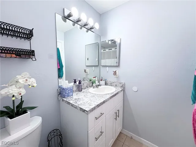 a bathroom with a granite countertop sink a light fixture and a mirror