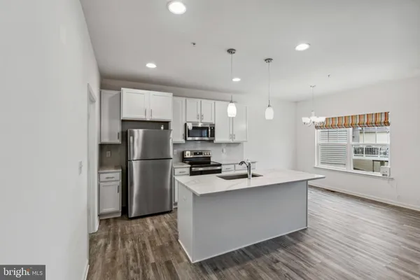 a kitchen with stainless steel appliances granite countertop a refrigerator a sink dishwasher a stove with wooden cabinets and floor
