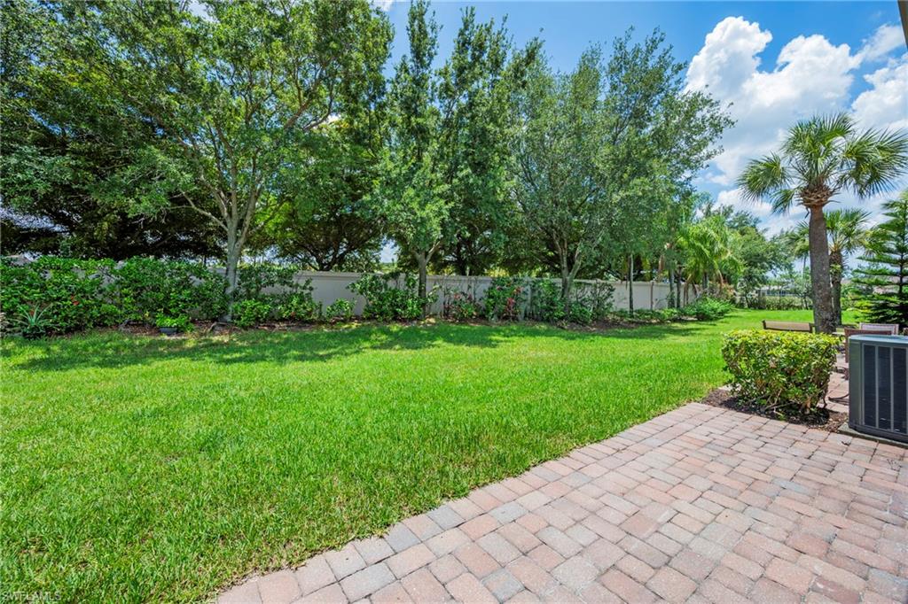 3916 Cherrybrook Loop Fort Myers, FL 33966 - Photo 22 of 31 Expansive backyard with verdant lawn, mature trees, and a paver patio