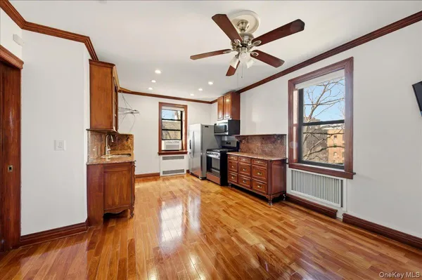 a kitchen with stainless steel appliances wooden floors and white walls
